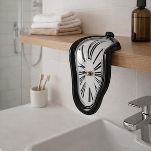 May include: A black and white melting clock with Roman numerals, mounted on a wooden shelf in a bathroom. The clock has a distorted, surreal design. Other bathroom items include a sink, towels, and a soap dispenser.