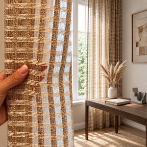 Peut inclure: Un panneau de rideau transparent présentant un motif à rayures verticales dans des tons alternés de beige et de crème. Le tissu possède une structure texturée à tissage ouvert qui laisse passer la lumière, créant un effet semi-transparent.