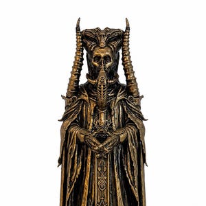 May include: A bronze-coloured statue of a skeletal figure wearing a hooded robe with intricate patterns and tall, curved horns. The figure holds a dark orb in its hands, and the rectangular base is inscribed with the name Asmodeus in raised letters.