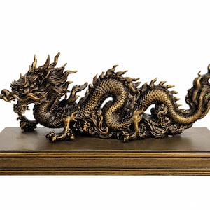 Op de afbeelding: Een bronskleurig drakenbeeldje met gedetailleerde schubben, een vloeiende manen en een lang, kronkelend lichaam. De draak bevindt zich in een horizontale, opgerolde houding op een rechthoekige, getrapte basis met een bijpassende afwerking.