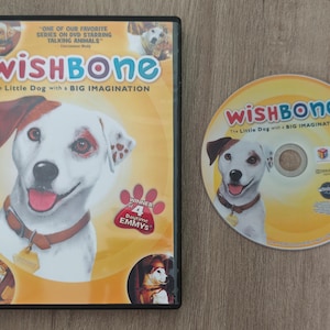 May include: DVD of "Wishbone: The Little Dog with a Big Imagination." The cover features a white dog with brown spots and a brown ear. The DVD is next to the case, with the same image of the dog. The case has the text "Winner 4 Daytime Emmys."
