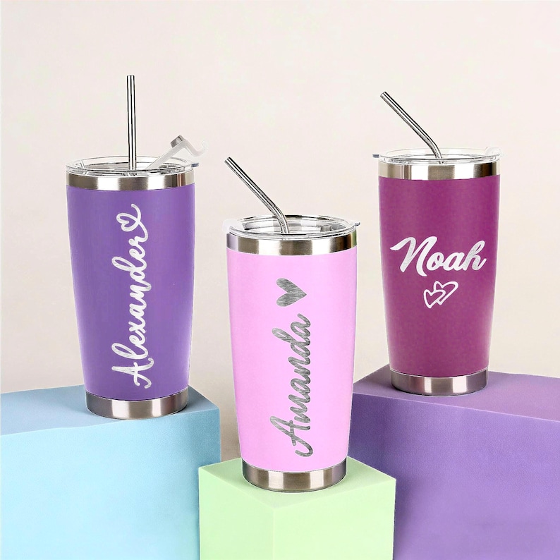 Puede incluir: Tres vasos de acero inoxidable en morado, rosa y magenta, cada uno con tapa y pajita plateadas. El vaso morado dice "Alexander", el rosa "Amanda" y el magenta "Noah".
