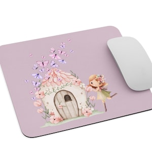 Könnte beinhalten: Ein lavendelfarbenes Mauspad mit einer skurrilen Illustration eines Feenhauses mit rosa Blumen und Schmetterlingen. Eine Cartoon-Fee steht in der Nähe. Eine weiße Computermaus befindet sich auf der rechten Seite des Mauspads.