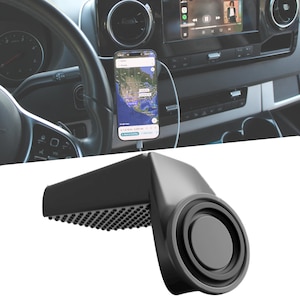 May include: A black car phone mount with a circular magnetic base and a textured surface. The phone mount is shown in a car, holding a smartphone displaying a map application. The car's dashboard and steering wheel are visible in the background.