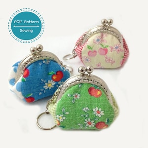 Könnte beinhalten: Drei kleine Münzbörsen mit Schlüsselanhängern. Die Börsen sind aus Stoff mit einem floralen und fruchtigen Druck. Die Börsen sind in Blautönen, Grün- und Gelbtönen.