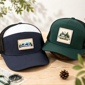 Könnte beinhalten: Zwei Trucker-Caps mit Mesh-Rücken. Eine ist marineblau mit weißer Front und einem Aufnäher mit der Aufschrift "printing logo". Die andere ist dunkelgrün mit einem Aufnäher mit der Aufschrift "Summer Camp". Beide haben einen schwarzen Mesh-Rücken und einen gebogenen Schirm.