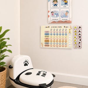 以下が含まれることがあります： 足跡のデザインが施された白と黒の幼児用トイレと、LES RÈGLES AU TOILETTEおよびJE DEVIENS PROPREというタイトルの2枚の壁掛けチャート。トイレの習慣を示すイラストと、丸いトークンが付いた週ごとの進捗トラッカーが含まれています。