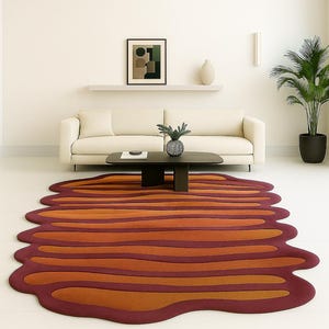 Wavy irregular burnt orange and rust hand tufted wool area rug styled in a modern living room with cream sofa and black coffee table.