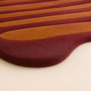 Close up of hand tufted wool rug showing thick plush pile and curved sculpted border detail.