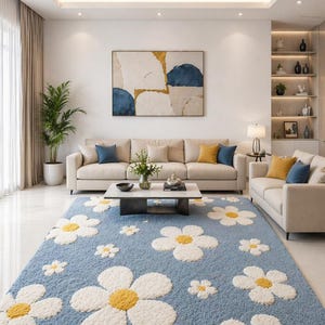 Könnte beinhalten: Hellblauer Shaggy-Teppich mit großen weißen und gelben Gänseblümchenmustern. Der Teppich befindet sich in einem Wohnzimmer mit beigem Sofa, Couchtisch und Kunstwerken. Der Raum hat eine moderne, luftige Atmosphäre.