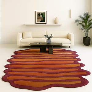 Irregular edge wool rug with layered wave design in rust and orange tones styled in minimalist decor space.