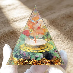 May include: A clear resin pyramid containing a copper wire tree with orange and white stone chips. The base features green and black mineral fragments, gold flakes, and a circular gold-colored metal ring inscribed with black runic characters.