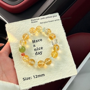 May include: A beaded bracelet with yellow and clear beads, a green bead, and a red bead. The bracelet is on a card that says "Have a nice day." The beads are 12mm in size.
