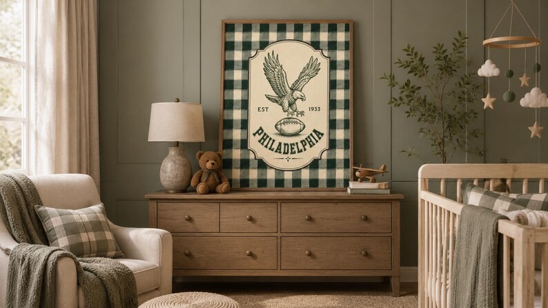 Pu&ograve; includere: Un quadro rettangolare incorniciato con uno sfondo a quadri scozzesi verde scuro e bianco. Al centro, un emblema color crema presenta un'illustrazione dettagliata di un'aquila, un pallone da football e il testo EST 1933 PHILADELPHIA.