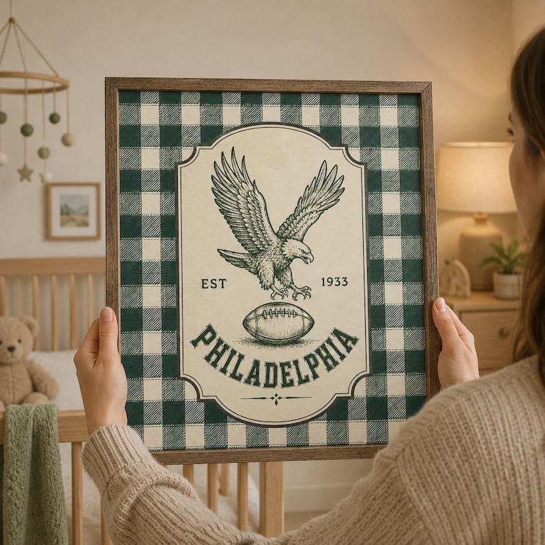 Pu&ograve; includere: Un quadro da parete incorniciato con uno sfondo a quadri scozzesi verde scuro e bianco. L'etichetta centrale color crema mostra un'illustrazione dettagliata di un'aquila sopra un pallone da football, con il testo EST 1933 e PHILADELPHIA.