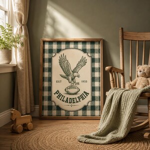 Pu&ograve; includere: Un quadro rettangolare incorniciato con uno sfondo a quadri scozzesi verde scuro e bianco. Al centro, un'etichetta color crema mostra un'aquila in volo, un pallone da football e il testo EST 1933 e PHILADELPHIA in inchiostro verde scuro.