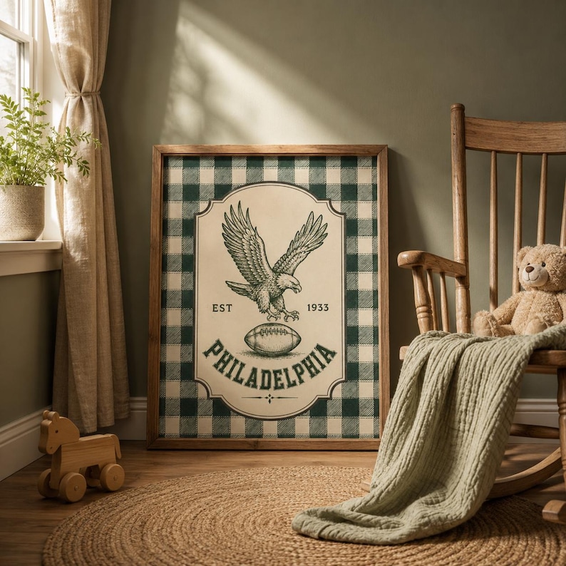 Pu&ograve; includere: Un quadro rettangolare incorniciato con uno sfondo a quadri scozzesi verde scuro e bianco. Al centro, un'etichetta color crema mostra un'aquila in volo, un pallone da football e il testo EST 1933 e PHILADELPHIA in inchiostro verde scuro.