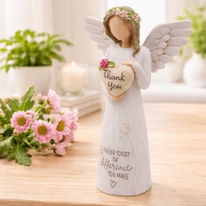 Puede incluir: Figura de ángel blanco sosteniendo un letrero en forma de corazón que dice "Thank You". El ángel tiene alas blancas, una corona floral y el texto "Never forget the difference you make" en la base.
