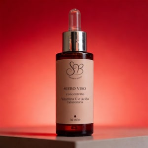 Può includere: Flacone di siero in vetro marrone con tappo e contagocce argentati. L'etichetta recita "SIERO VISO concentrato, Vitamina C e Acido Ialuronico" e "30 ml e". Lo sfondo è un gradiente di rosso.