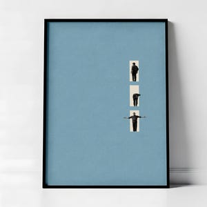May include: A framed art print featuring a light blue background with three rectangular cutouts. Each cutout contains a black and white image of a person in different poses. The frame is black.
