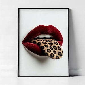 May include: A framed art print featuring a close-up of red lips with a leopard print tongue extending out. The artwork is set against a white background, with a black frame.