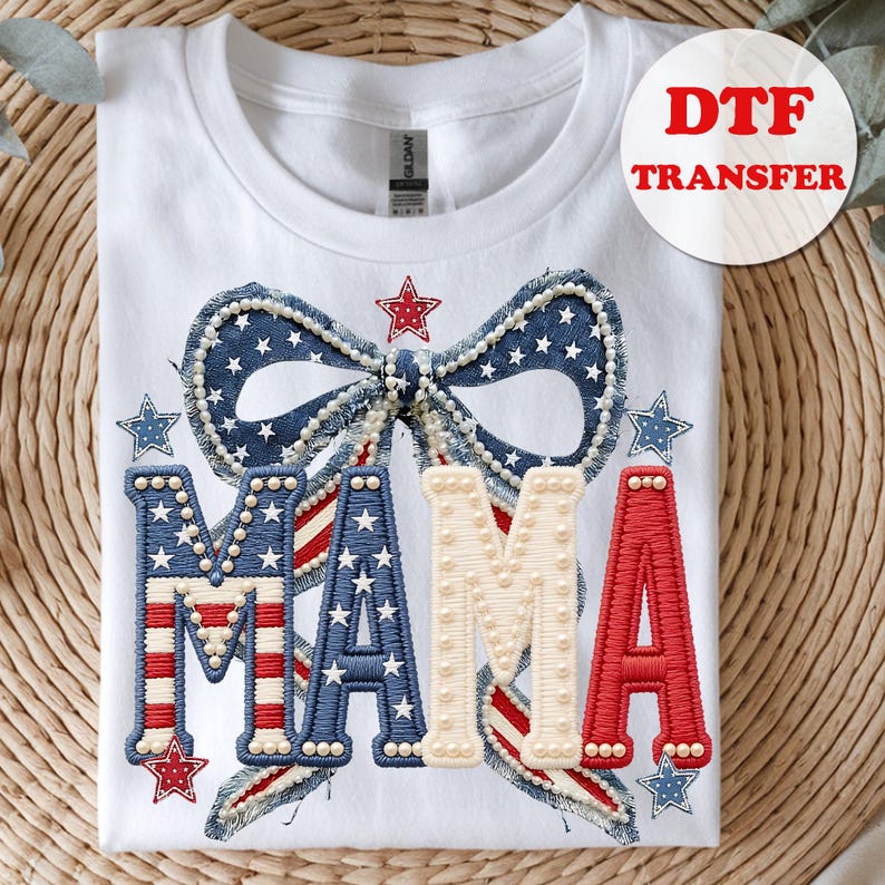 May include: White t-shirt with a patriotic design featuring the word "MAMA" in red, white, and blue. The design includes a bow, stars, and pearl accents, with "DTF TRANSFER" in a circle.