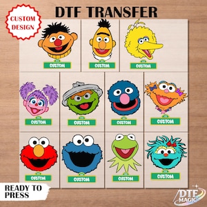 May include: A sheet of DTF (Direct to Film) transfers featuring colorful cartoon character designs. Each character has a "CUSTOM" label below. The sheet includes the text "DTF TRANSFER", "CUSTOM DESIGN", and "READY TO PRESS".