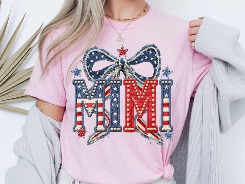 May include: Pink t-shirt featuring a patriotic design with the word "MIMI" in red, white, and blue. The design includes a bow and stars, creating a festive and celebratory look. The shirt is a casual wear item.