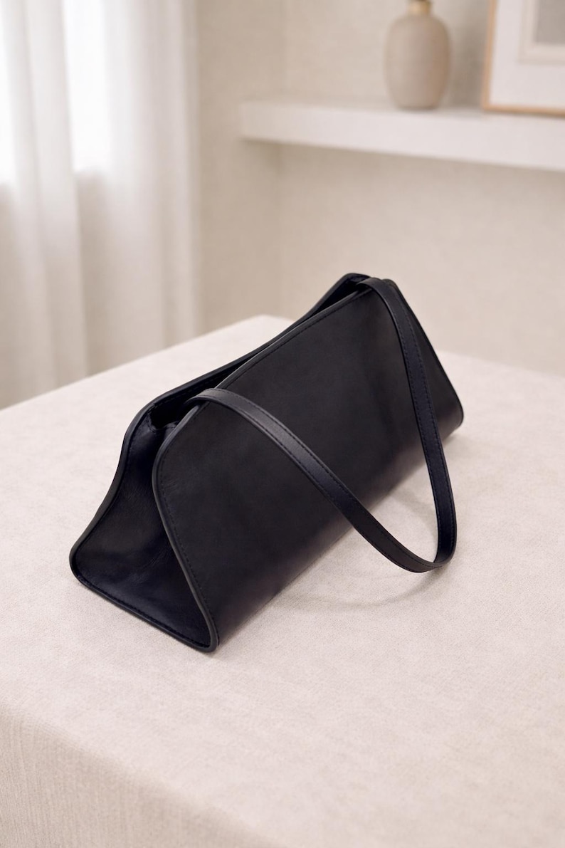 Minimalist women leather bag in black with structured baguette bag silhouette, sleek shoulder bag featuring smooth genuine leather and curved design, elegant top handle handbag with crossbody strap option, aesthetic bag inspired by 90s baguette bag and pinterest trends, everyday bag for casual and work use, zipper closure leather purse with compact functionality, classic handbag with quiet luxury style, minimalist work bag and trendy everyday bag, perfect gift for women