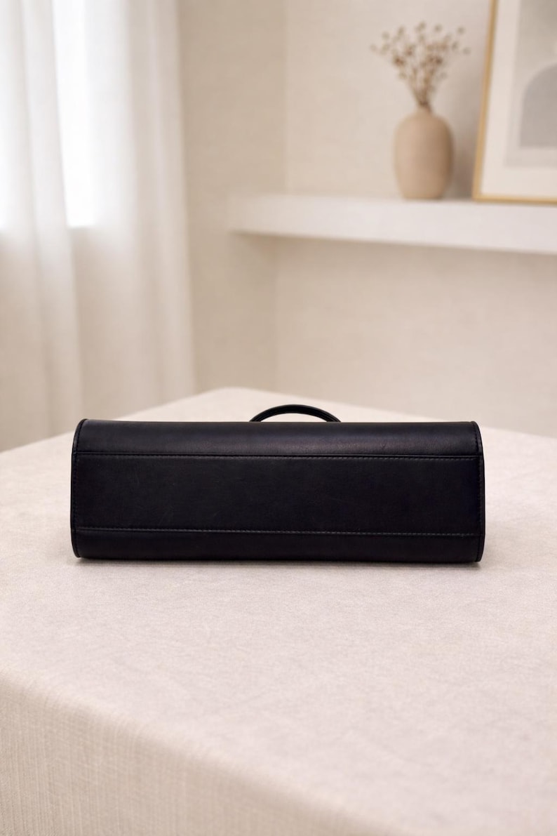 Black leather baguette handbag with minimalist design and structured silhouette, women shoulder bag crafted from soft genuine leather, top handle bag with detachable strap for crossbody wear, elegant aesthetic bag inspired by vintage baguette bag and 90s underarm bag trend, everyday bag with zipper closure for essentials, sleek and slim leather purse ideal for minimalist work bag use, classic handbag with quiet luxury appeal, trendy everyday bag and thoughtful gift for women