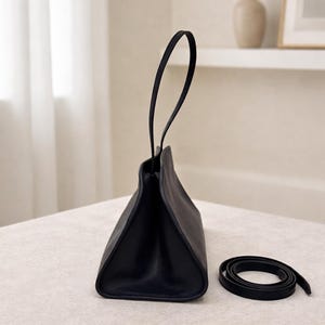Elegant black leather shoulder bag with minimalist baguette handbag design, structured leather bag crafted from soft genuine leather, top handle bag with detachable strap for crossbody bag versatility, aesthetic pinterest bag inspired by vintage baguette bag and 90s fashion trend, everyday bag for daily essentials, zipper closure for secure storage, sleek and slim shoulder bag perfect as minimalist work bag, classic handbag with quiet luxury feel, designer style women leather bag gift