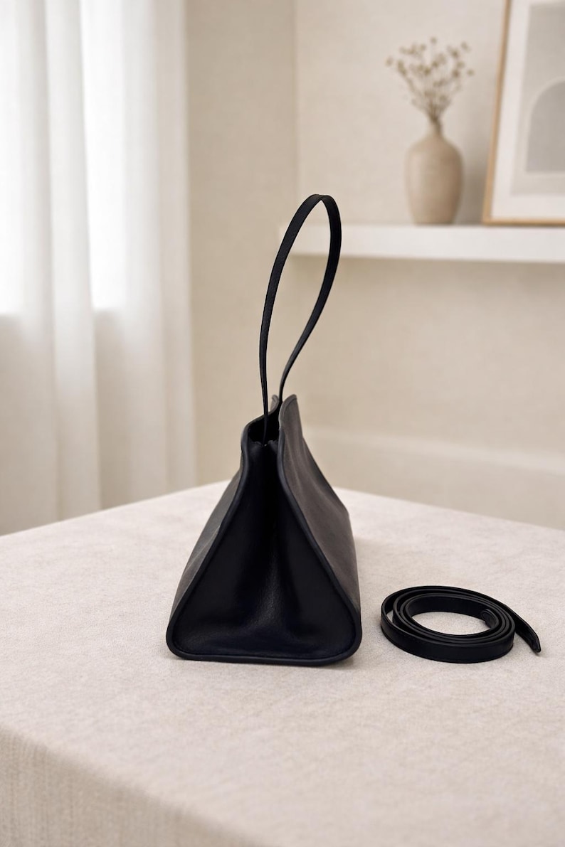 Elegant black leather shoulder bag with minimalist baguette handbag design, structured leather bag crafted from soft genuine leather, top handle bag with detachable strap for crossbody bag versatility, aesthetic pinterest bag inspired by vintage baguette bag and 90s fashion trend, everyday bag for daily essentials, zipper closure for secure storage, sleek and slim shoulder bag perfect as minimalist work bag, classic handbag with quiet luxury feel, designer style women leather bag gift