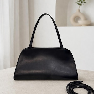 Black leather baguette bag for women displayed on a neutral background, minimalist shoulder bag with structured silhouette and sleek top handle design, elegant leather shoulder bag inspired by 90s baguette bag trend, aesthetic pinterest bag perfect as everyday bag, soft genuine leather purse with zipper closure, versatile underarm bag and convertible crossbody bag, classic handbag ideal for daily essentials, minimalist work bag, quiet luxury style women leather bag, gift for women, slim bag