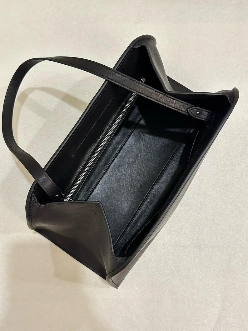 Black minimalist leather baguette bag with clean structured silhouette, women shoulder bag featuring soft genuine leather and sleek top handle design, elegant handbag inspired by 90s baguette bag and underarm bag trend, aesthetic pinterest bag perfect as everyday bag or minimalist work bag, zipper closure leather purse with compact storage, convertible crossbody bag option, classic handbag with quiet luxury style, trendy everyday bag for modern outfits, ideal gift for women