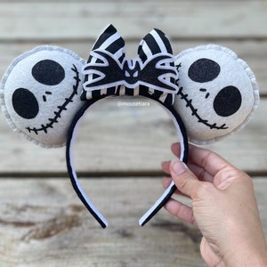 May include: Black and white striped bow with a bat design, attached to a white headband with two white felt ears featuring the face of Jack Skellington from The Nightmare Before Christmas.  @mousetiara