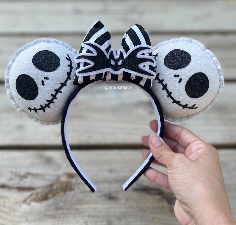 May include: Black and white striped bow with a bat design, attached to a white headband with two white felt ears featuring the face of Jack Skellington from The Nightmare Before Christmas.  @mousetiara