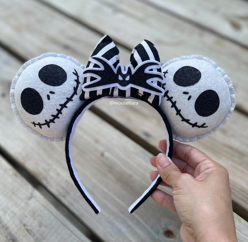 May include: Black and white striped bow with a bat design, attached to a white headband with two white felt ears featuring a black and white Jack Skellington face.  @mousetiara