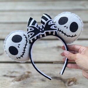 May include: Black and white striped bow with a bat design, attached to a black headband with white felt ears featuring Jack Skellington's face.  @mousetiara