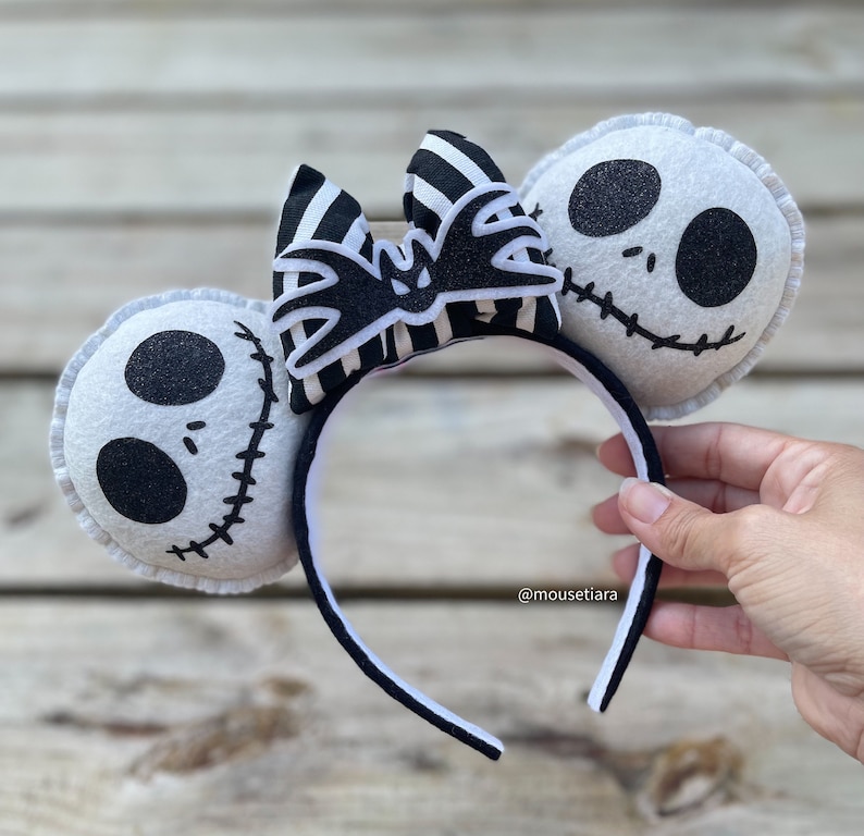 May include: Black and white striped bow with a bat design, attached to a black headband with white felt ears featuring Jack Skellington's face.  @mousetiara