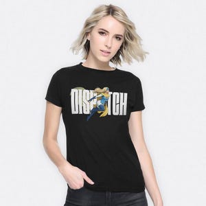 以下が含まれることがあります： 「DISPATCH」の文字が大きく白でプリントされた黒いTシャツ。その下に、青と黄色を基調としたブロンドのスーパーヒーローの漫画イラストが描かれています。Tシャツは半袖です。