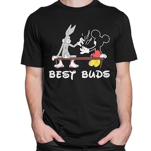 May include: Black t-shirt with a cartoon image of Bugs Bunny and Mickey Mouse sharing a lit object. The words "BEST BUDS" are printed in white below the characters. The characters are sitting on a brown bench.
