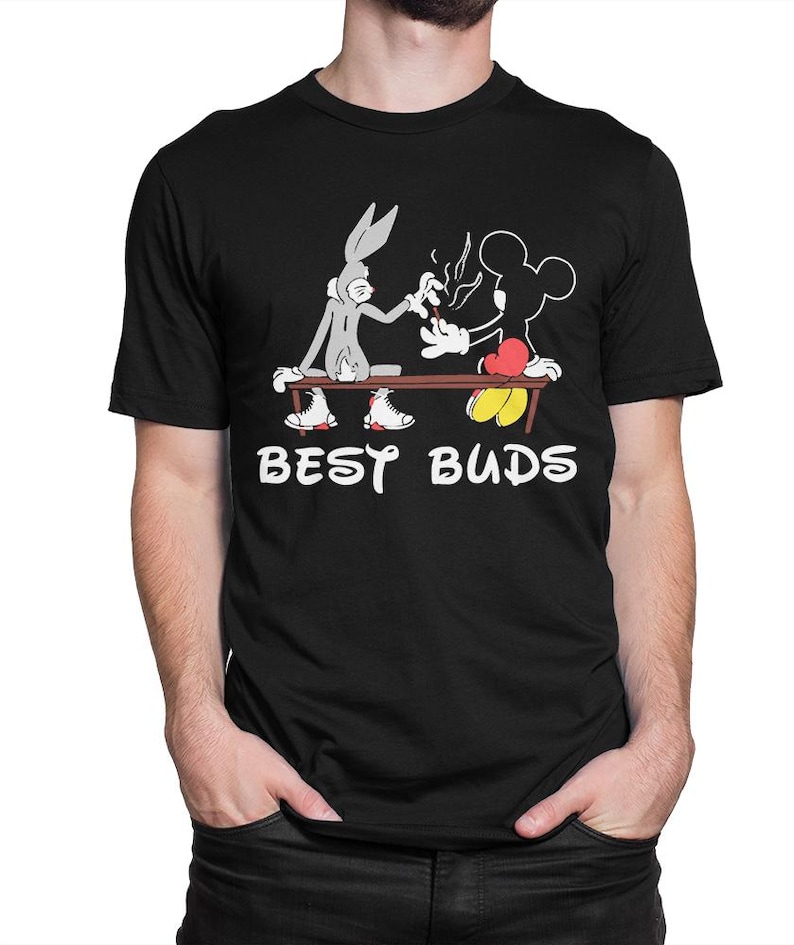 May include: Black t-shirt with a cartoon image of Bugs Bunny and Mickey Mouse sharing a lit object. The words "BEST BUDS" are printed in white below the characters. The characters are sitting on a brown bench.
