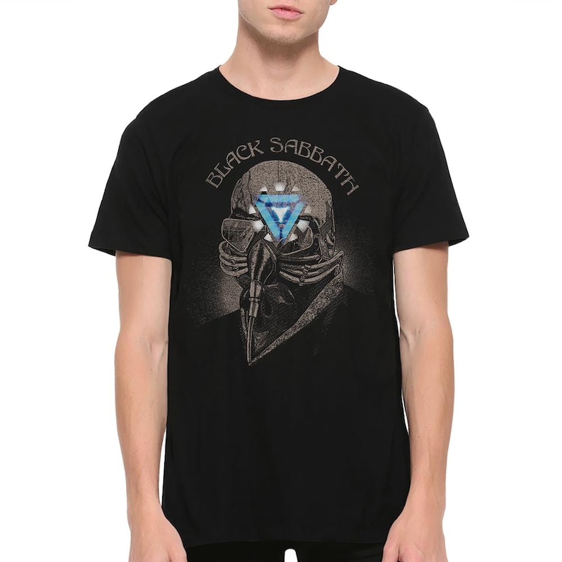 May include: Black t-shirt featuring a graphic of a skull with a respirator and a blue triangle design. The text "BLACK SABBATH" is arched above the skull. The shirt is a classic crew neck.