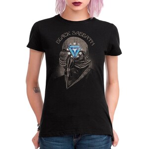 May include: Black t-shirt featuring a graphic of a skeletal figure with a respirator and a blue triangle. The text "BLACK SABBATH" is arched above the figure. The shirt is a classic crew neck.