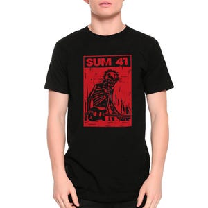 Könnte beinhalten: Schwarzes T-Shirt mit roter Grafik. Die Grafik zeigt den Text "SUM 41" über einem Gitarre spielenden Skelett. Das Design hat eine Punkrock-Ästhetik.