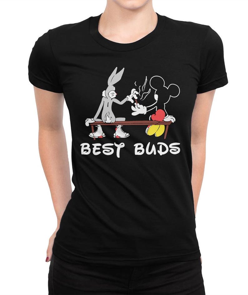 May include: Black t-shirt with a graphic of Bugs Bunny and Mickey Mouse sharing a cigarette, with the words "BEST BUDS" in white. The cartoon characters are seated on a bench. The shirt has a crew neck.