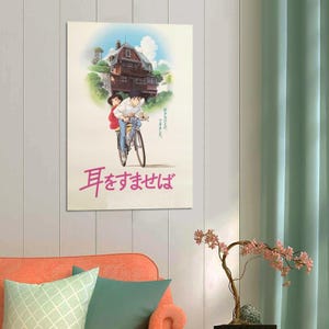 May include: A poster featuring an anime-style illustration of two people riding a bicycle. The background shows a house on a hill under a blue sky. The poster has Japanese text in pink.