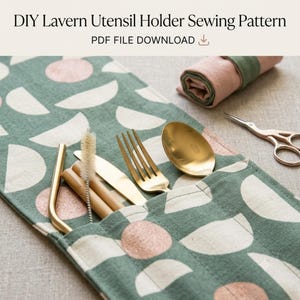 May include: A fabric utensil holder featuring a green background with a pattern of white and pink semi-circles and circles. The holder contains a gold spoon, a gold fork, a gold knife, a straw, and a cleaning brush. Text reads: DIY Lavern Utensil Holder Sewing Pattern PDF FILE DOWNLOAD.