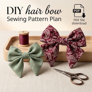 May include: A DIY hair bow sewing pattern plan PDF file download featuring two fabric hair bows. One bow is sage green with gold polka dots, and the other is deep red with a white paisley pattern. A spool of thread and small scissors are included.