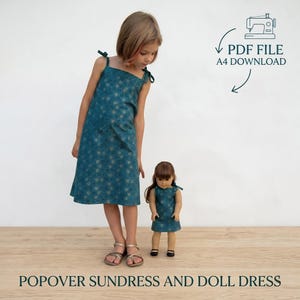 May include: A teal popover sundress with a gold floral pattern, worn by a young girl, and a matching doll dress. The dresses have tie straps. The image includes the text "PDF FILE A4 DOWNLOAD".